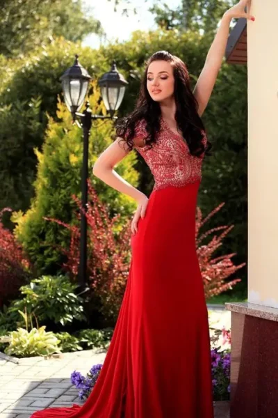Iris smiling in red dress, standing in garden