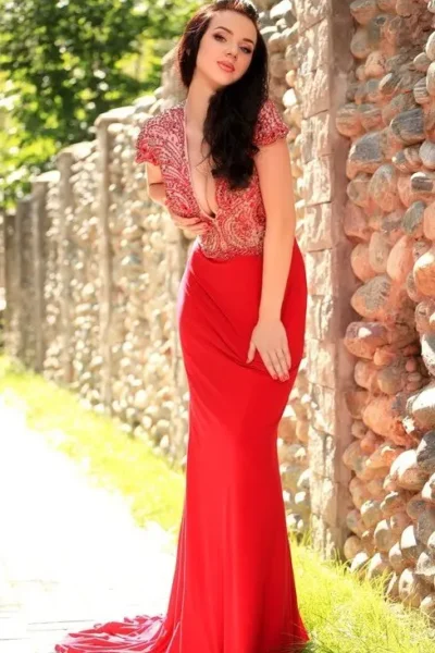Iris in long red dress, posing near stone wall