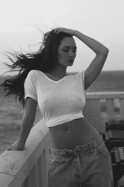 Rosie Red outdoors in a white crop top, wind in her hair